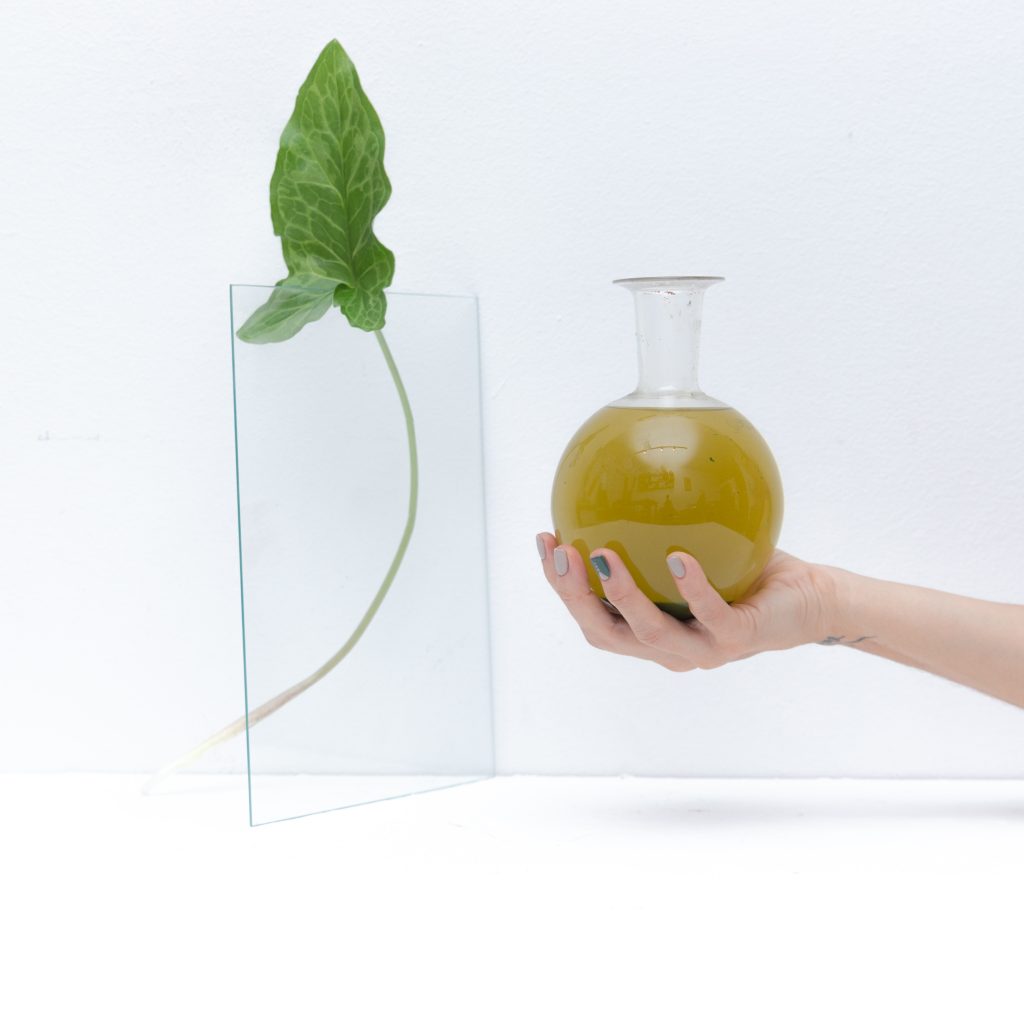 mano sosteniendo frasco de laboratorio con preparado herbal